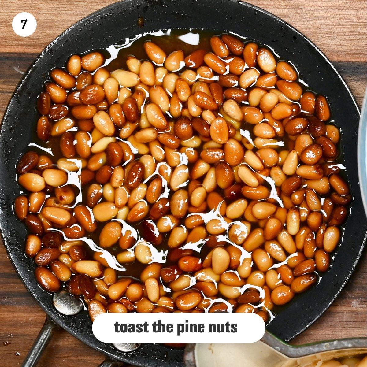 Close up view of golden brown toasted pine nuts on a skillet
