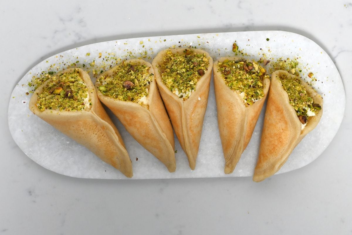 Cream-filled asafiri qatayef neatly arranged on a white marble plate.