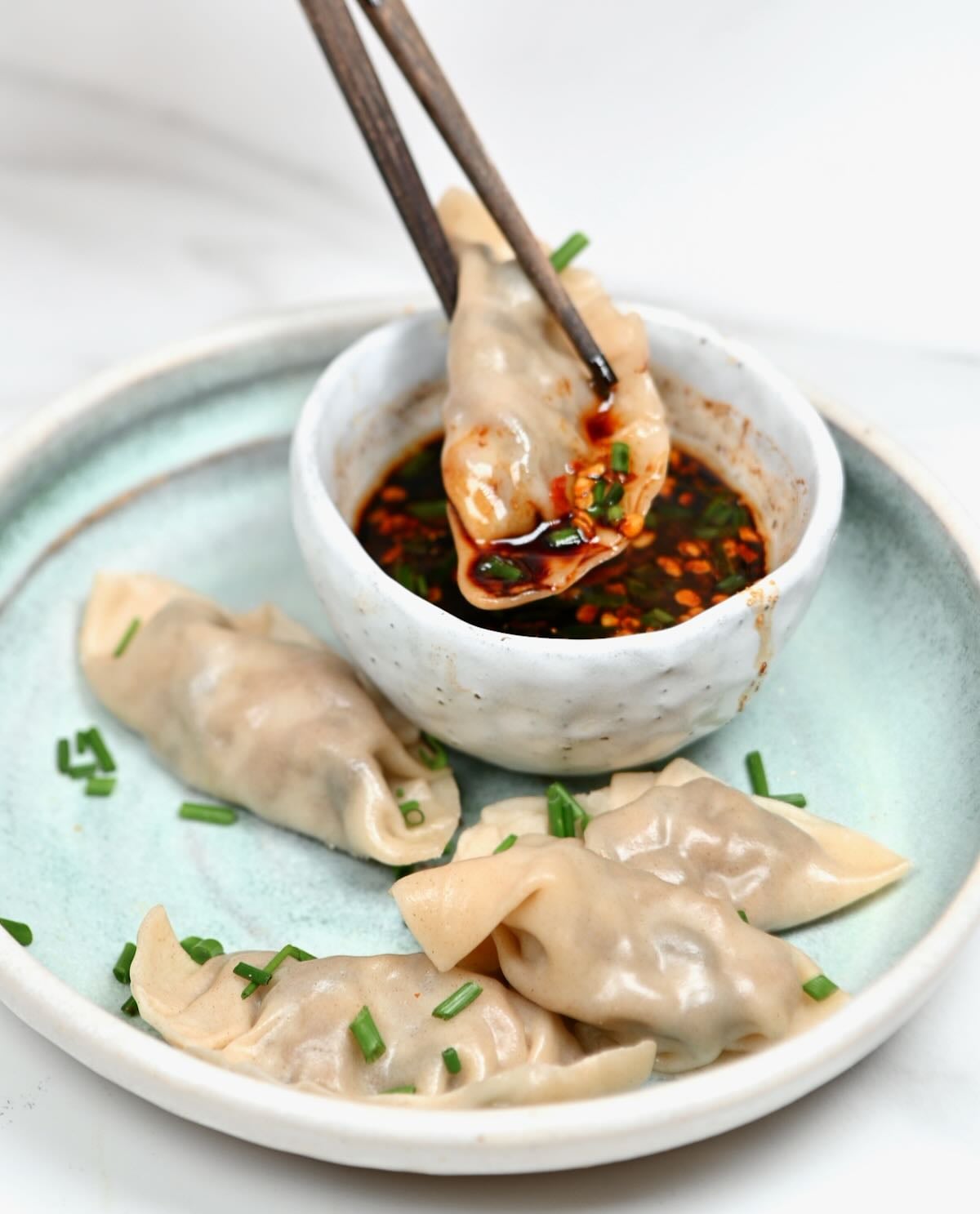 A dumpling being dipped into homemade dumpling sauce.