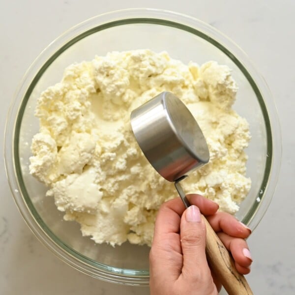 Adding heavy cream to milk curds.