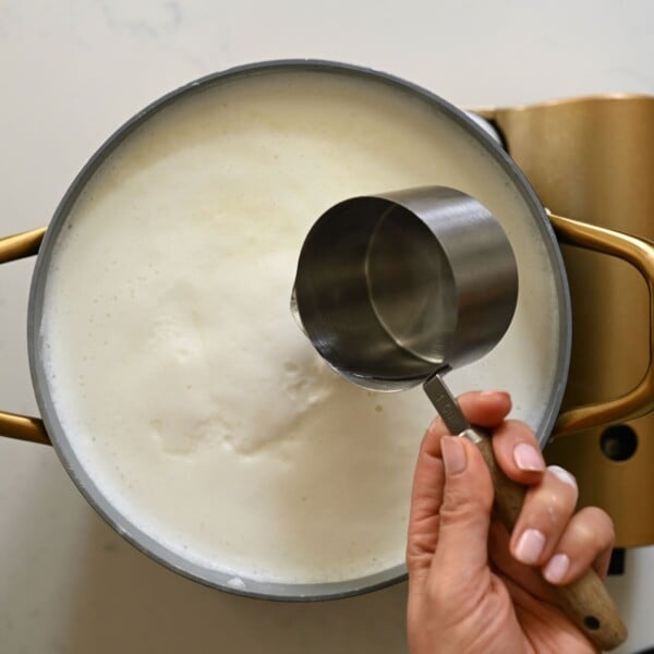 Adding white vinegar to heated milk.