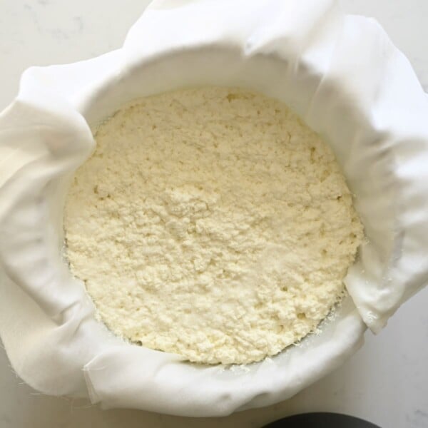 Draining milk curds over cheesecloth.