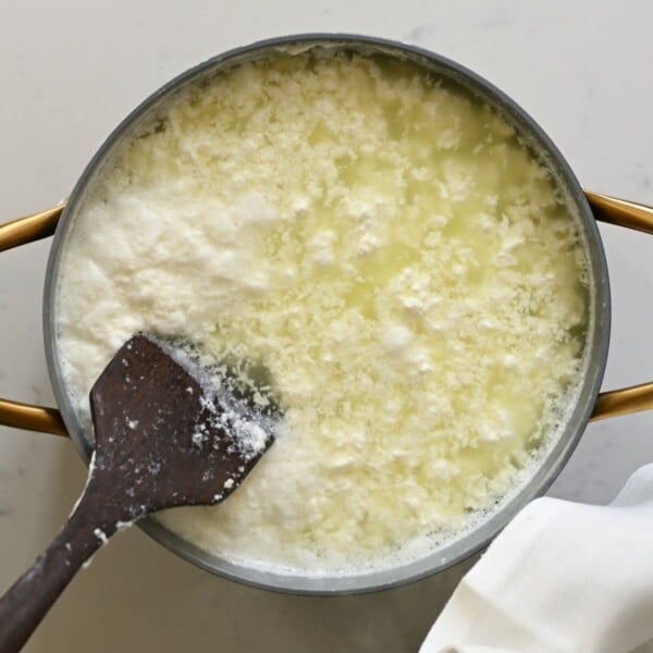 Gently stirring the milk curds in a large pot.