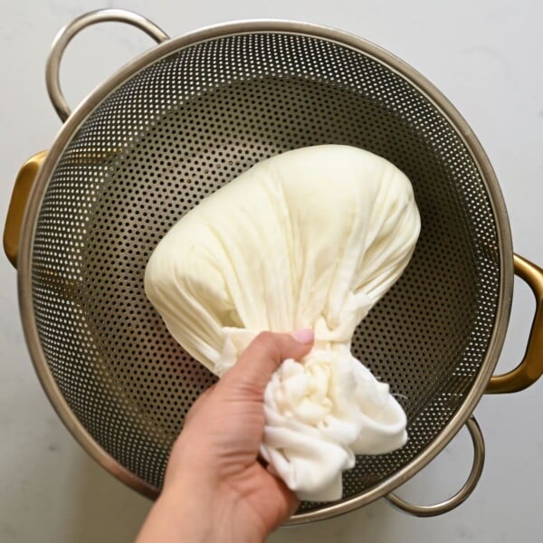 Squeezing milk curds in a cheesecloth.