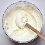 A spoonful of homemade cream cheese inside a container.