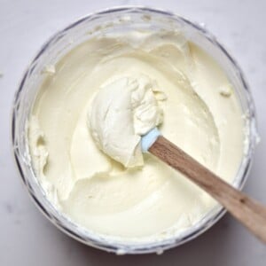 A spoonful of homemade cream cheese inside a container.