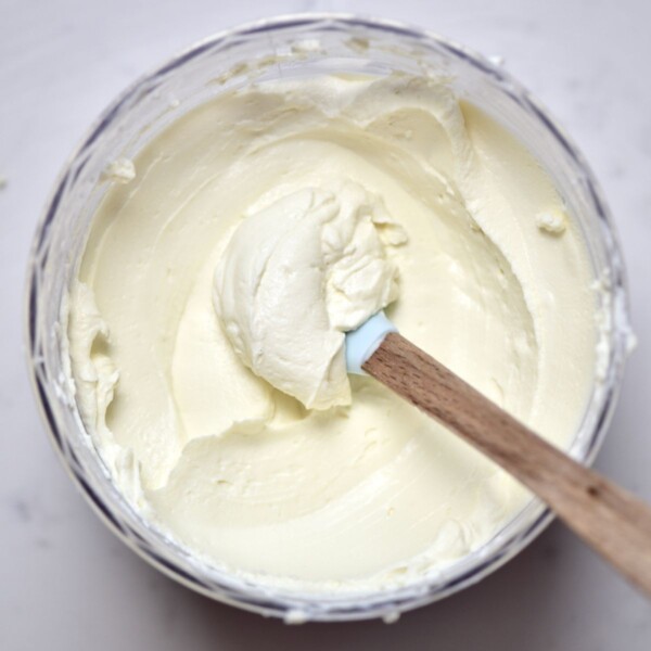A spoonful of homemade cream cheese inside a container.