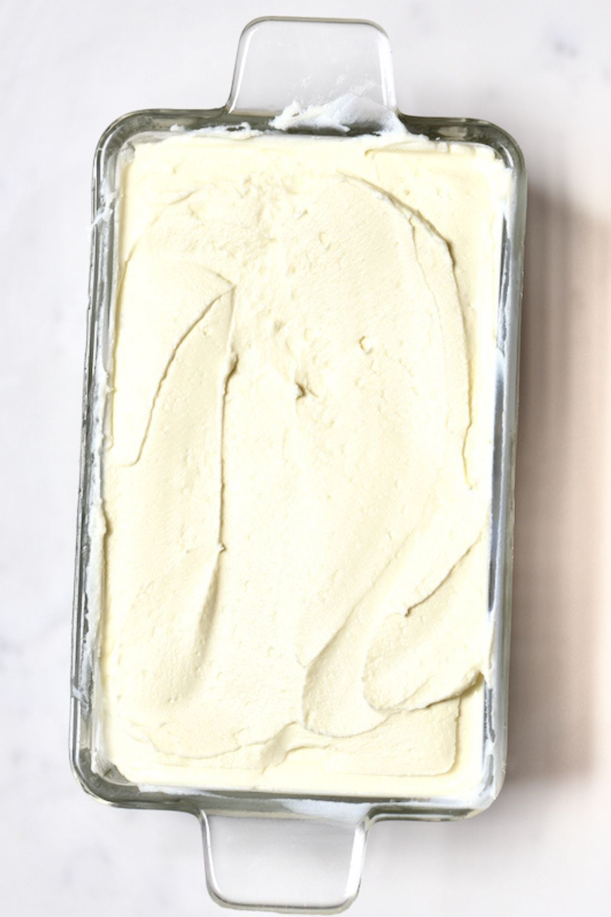 A glass container filled with homemade cream cheese.