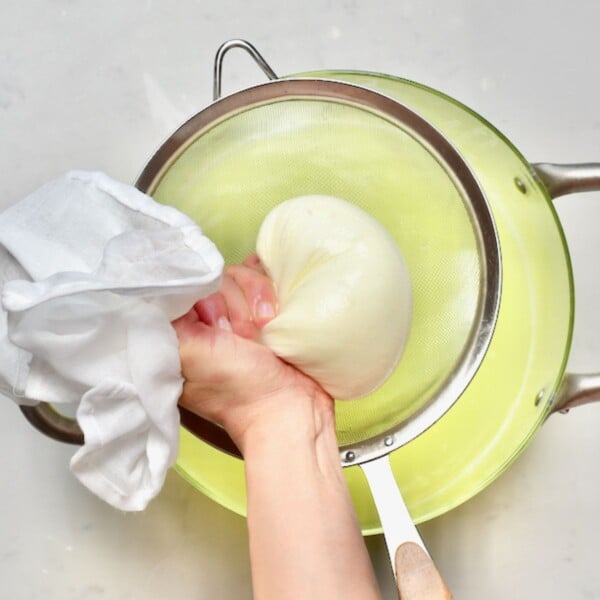 Squeezing the whey out of cream cheese milk curds.