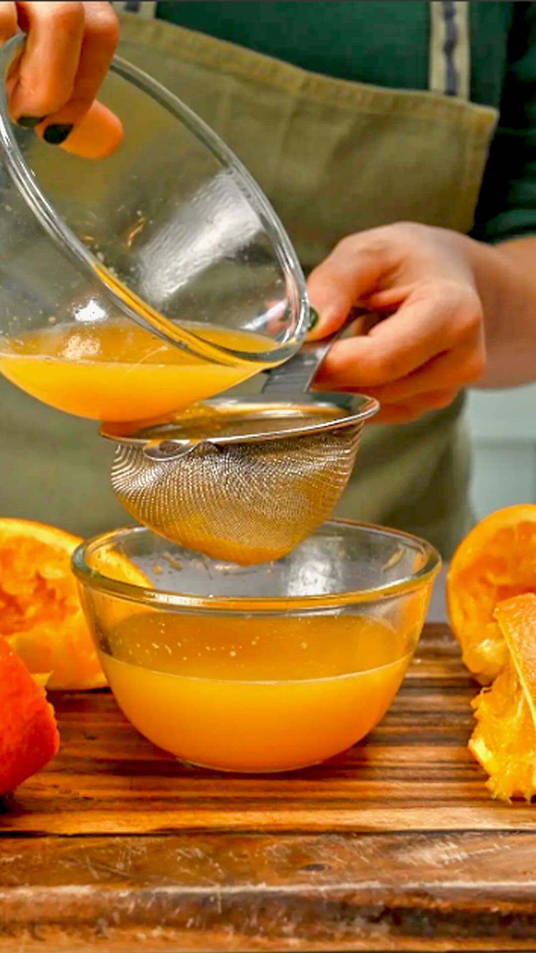 Sieving orange juice over a bowl.