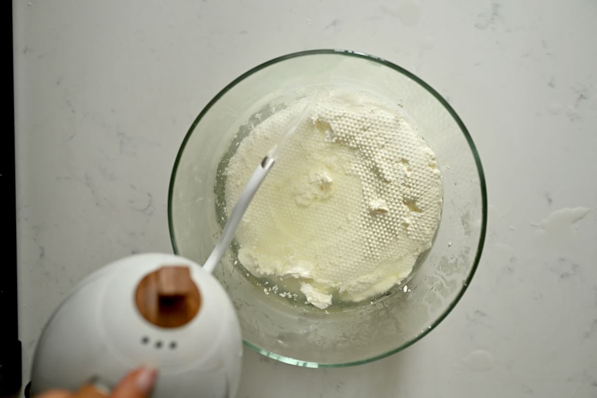 Adding hot water to the drained cheese curds.