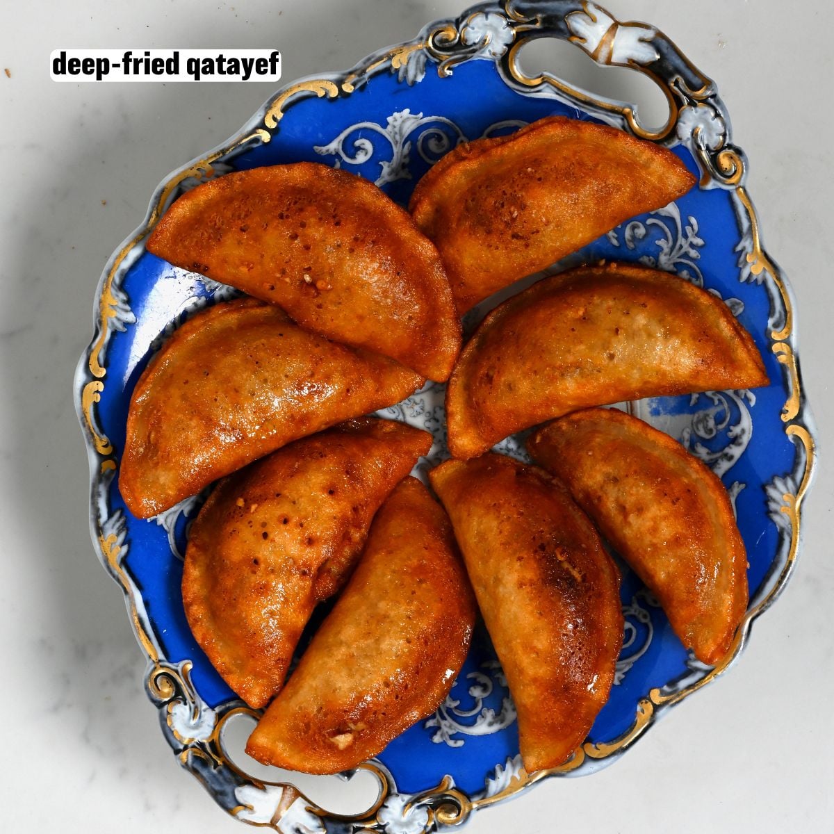 Plate of golden-brown, deep-fried qatayef, crispy on the outside.