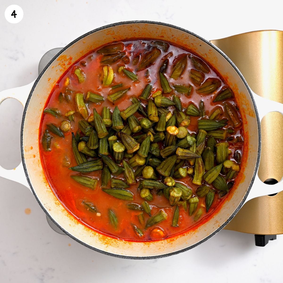 Pre-cooked okra added to a tomato and beef sauce to simmer.