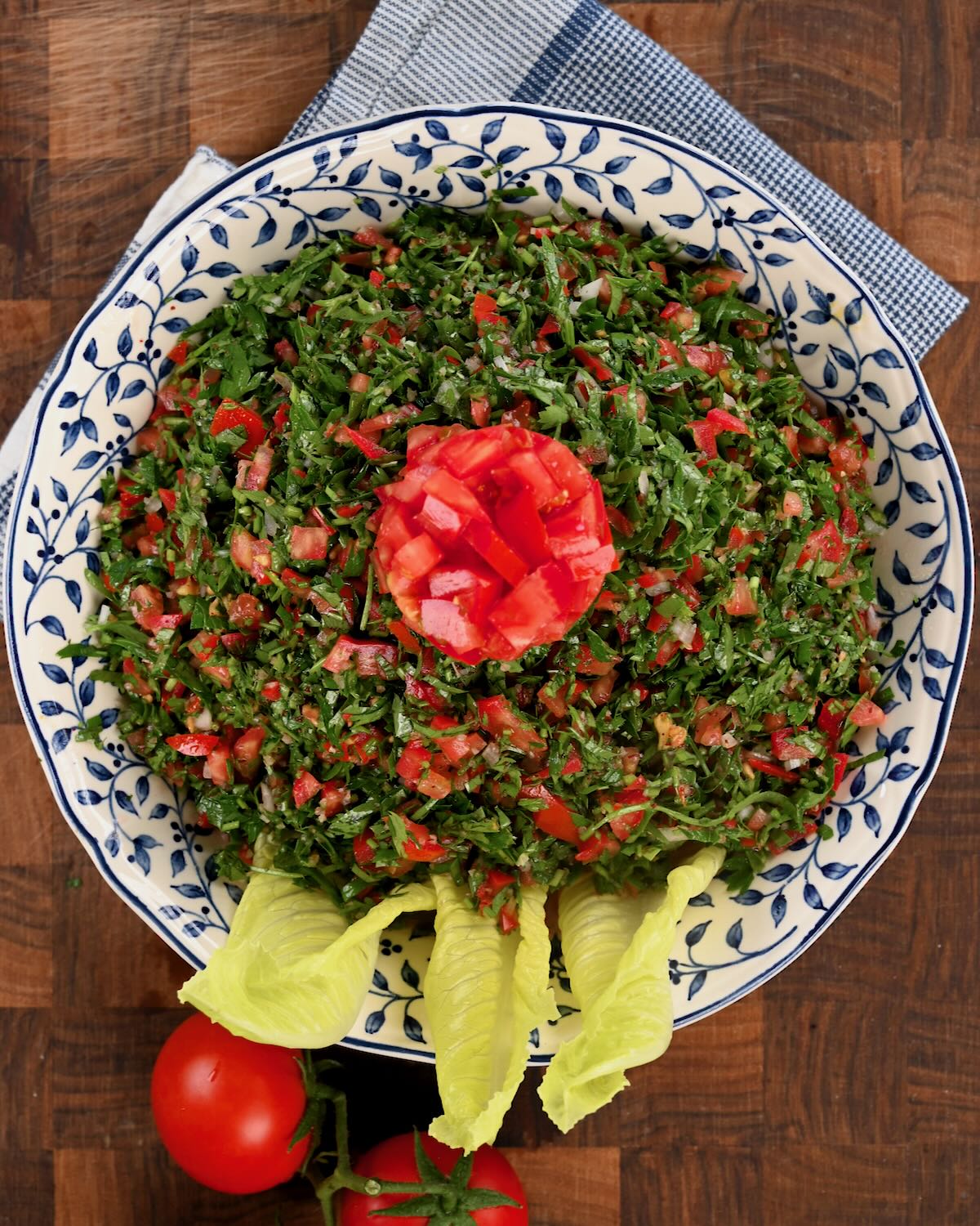 Tabbouleh salad served on a plate with a few lettuce leaves. - 1