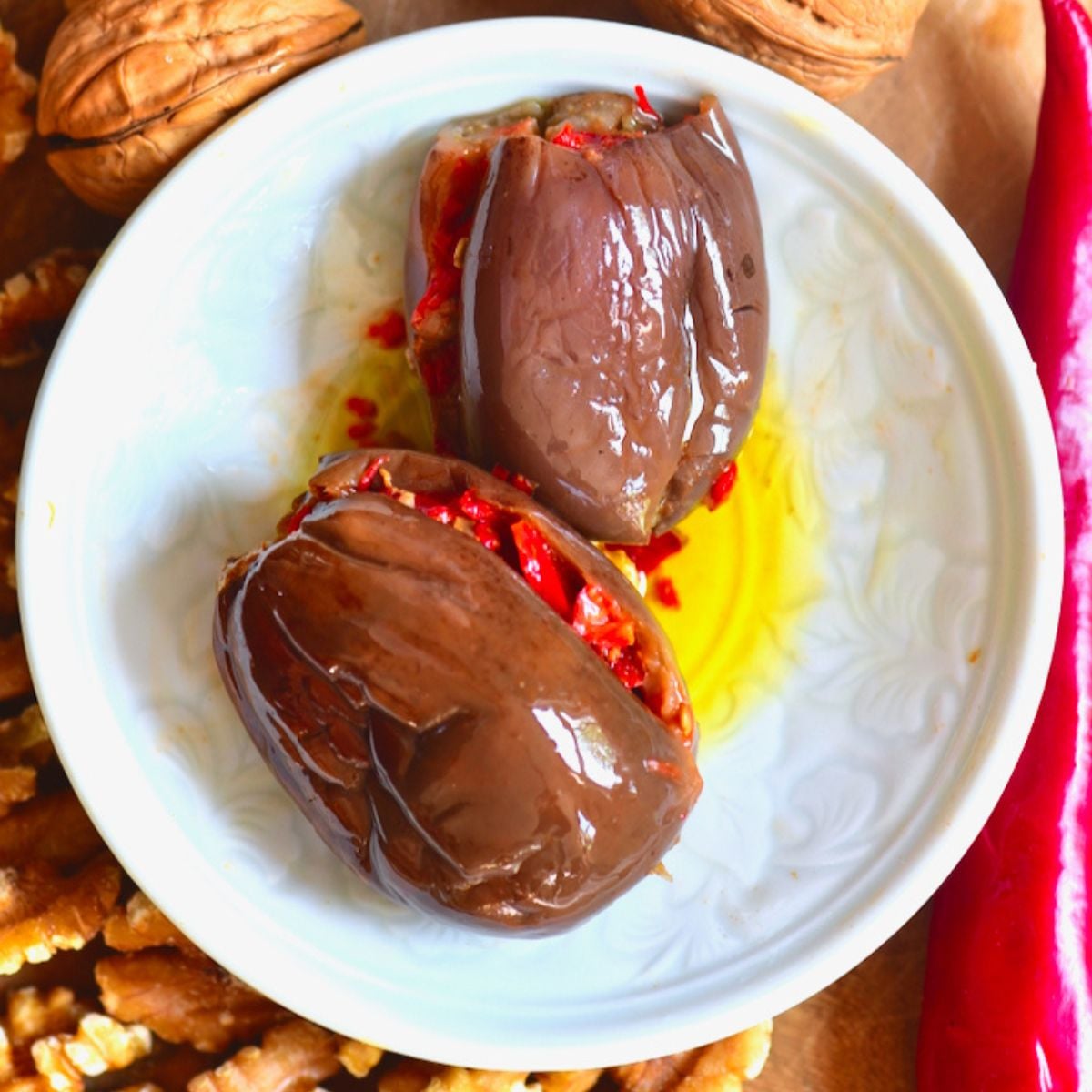 Two stuffed makdous eggplants served on a white plate.