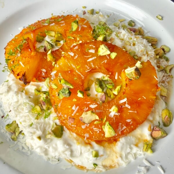 close up of Cottage cheese topped with caramelized pineapple rings, pistachios, coconut flakes, and lime zest.