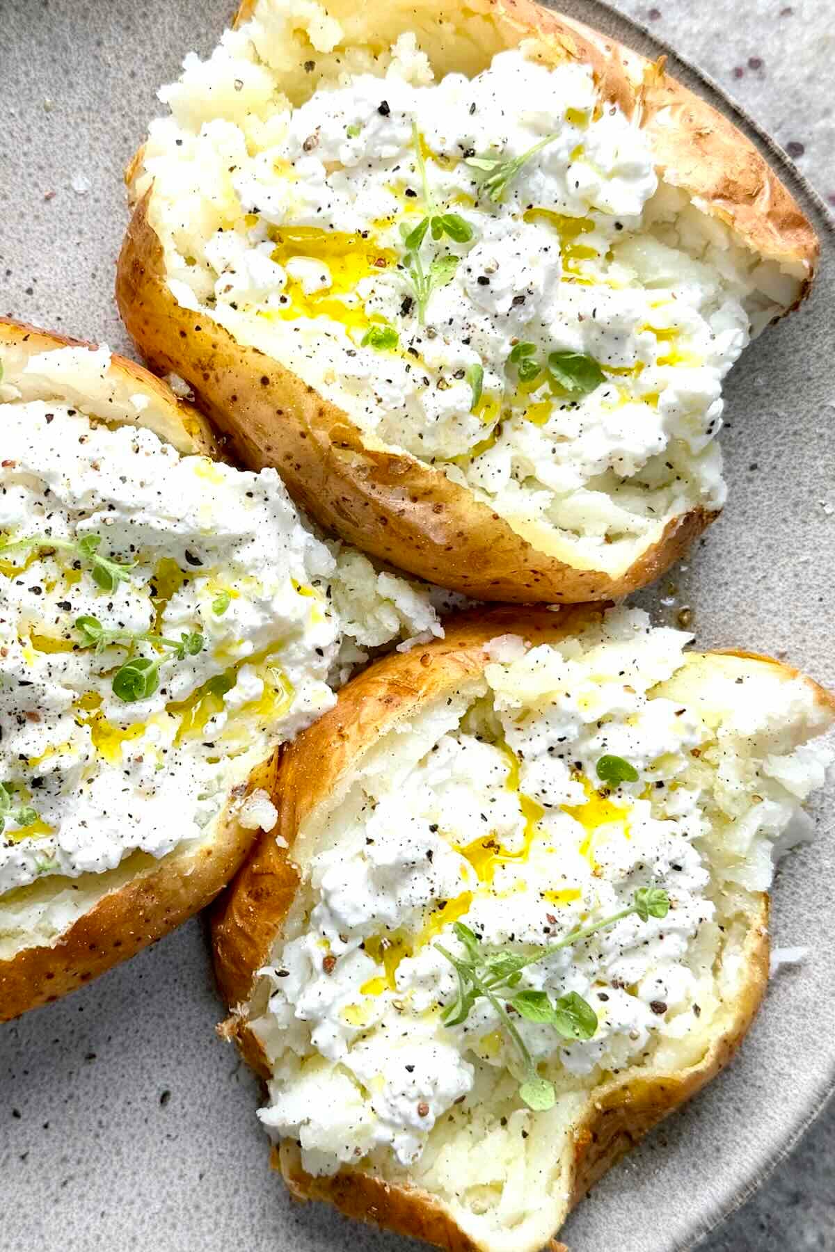 Baked potatoes filled with cottage cheese, olive oil, cracked black pepper, and microgreens.