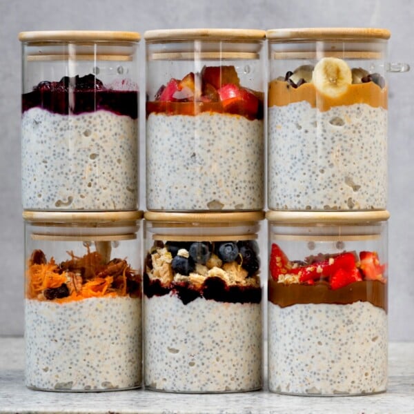 side view of 6 glass jars of overnight oats with different toppings