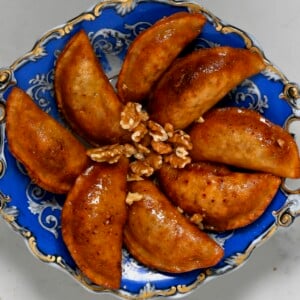 square photo of eight fried qatayef on a blue plate