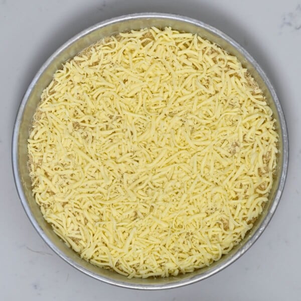 Kataifi topped with mozzarella in a baking pan.