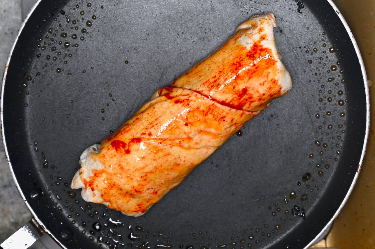 Shawarma wrap brushed with spiced oil in a skillet before crisping.