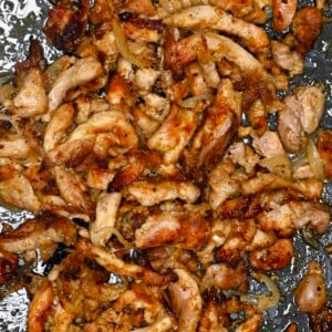 top-down close-up of chicken shawarma strips and onions with browned, crispy bits on a pan.