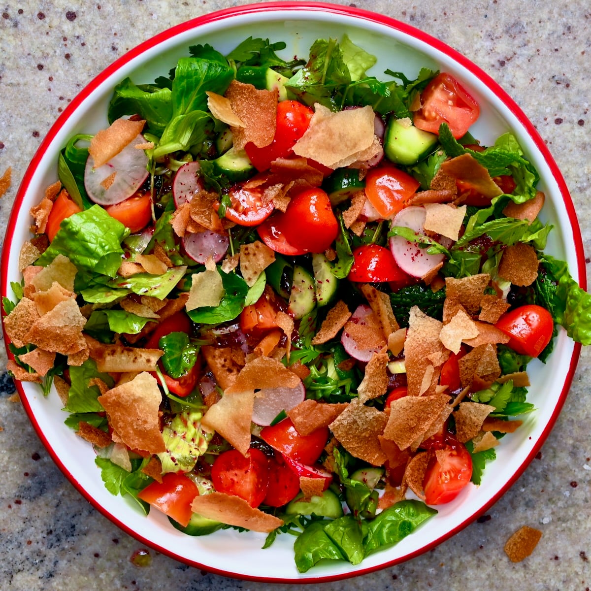Lebanese fattoush salad in a bowl with romaine, cucumber, tomatoes, radishes, herbs, and crispy pita chips.