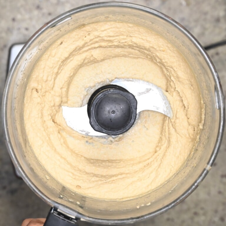 Hummus blended in a food processor with a thick, slightly textured consistency.
