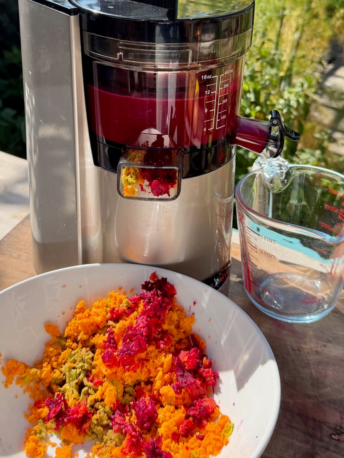 A juicer making ABC juice with the pulp coming out into a bowl.