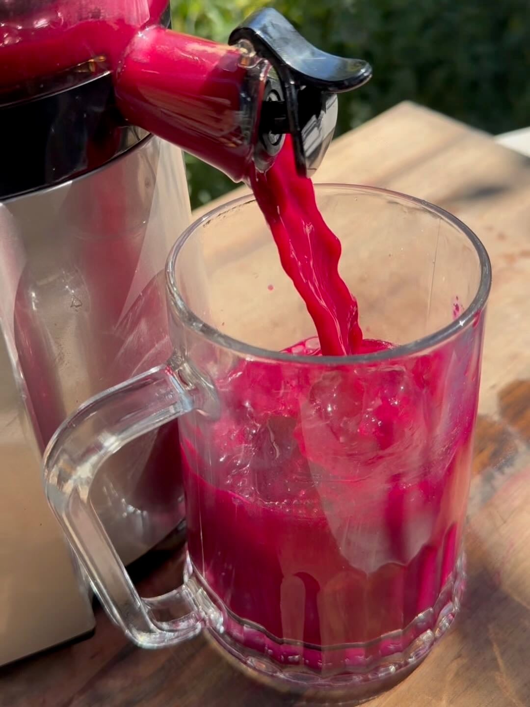 ABC juice being poured from the juicer into a glass with ice cubes.