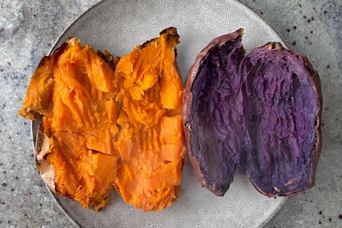 Two sweet potatoes cooked in air fryer and cut open in half.