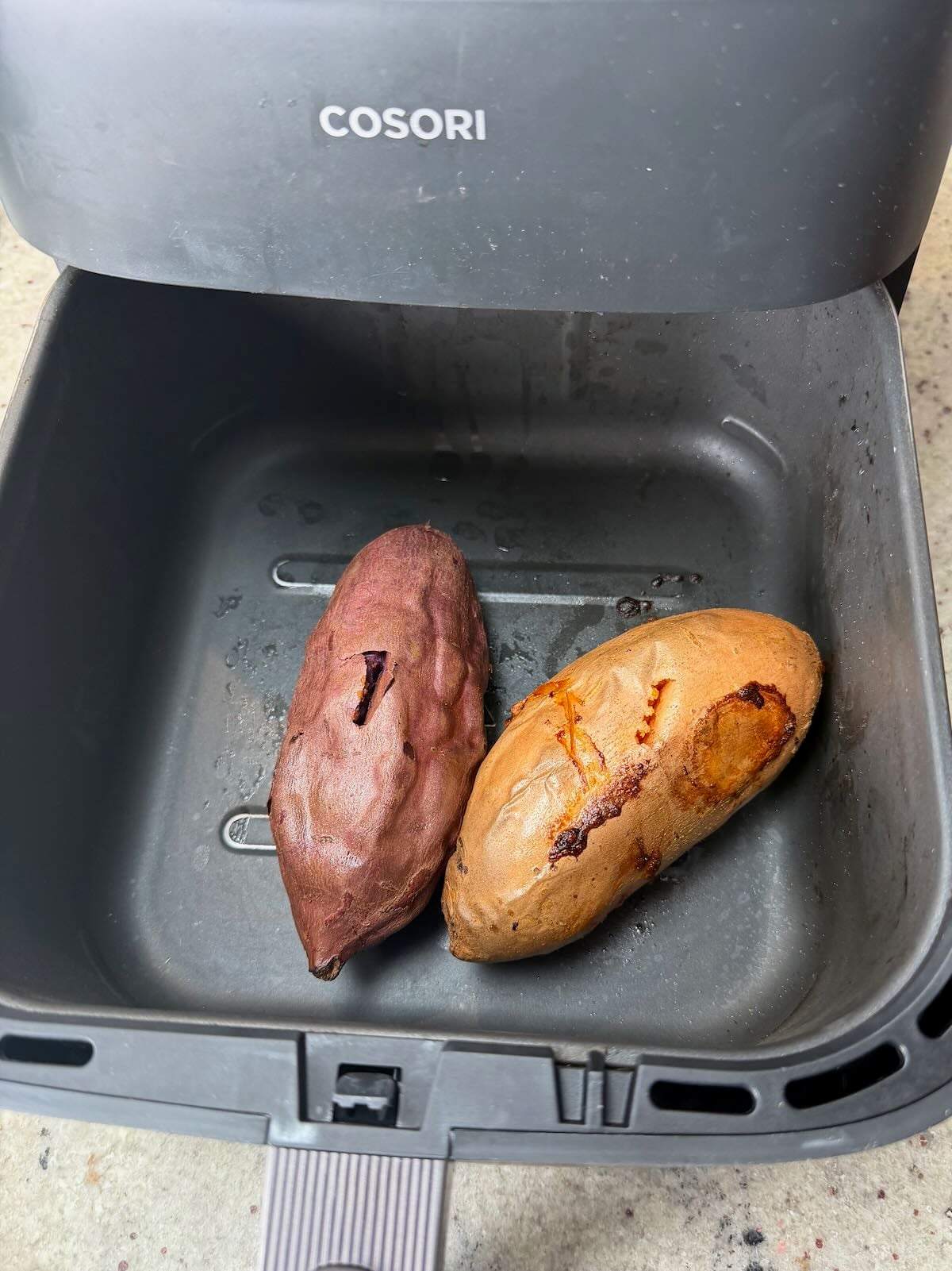 Two sweet potatoes in an air fryer basket.