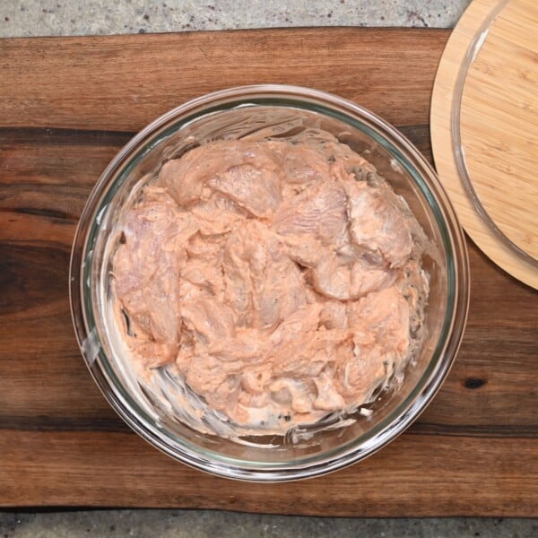 Chicken tenders mixed into yogurt marinade.