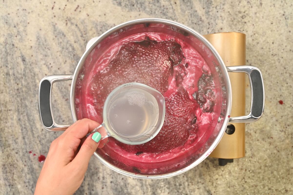 Adding liquid pectin to cherry jam.