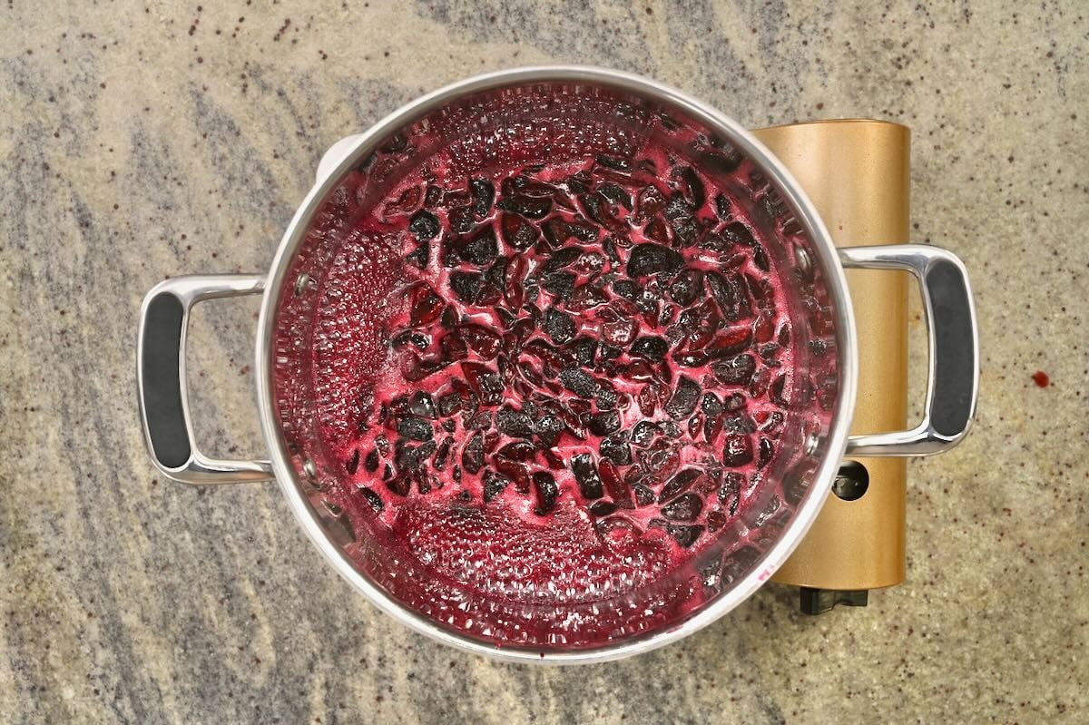 Boiling cherries and sugar in a large saucepan.