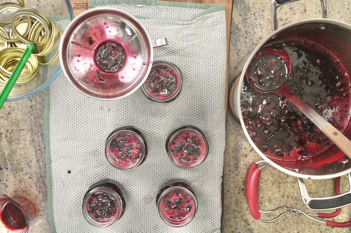 Filling small jars with cherry jam.