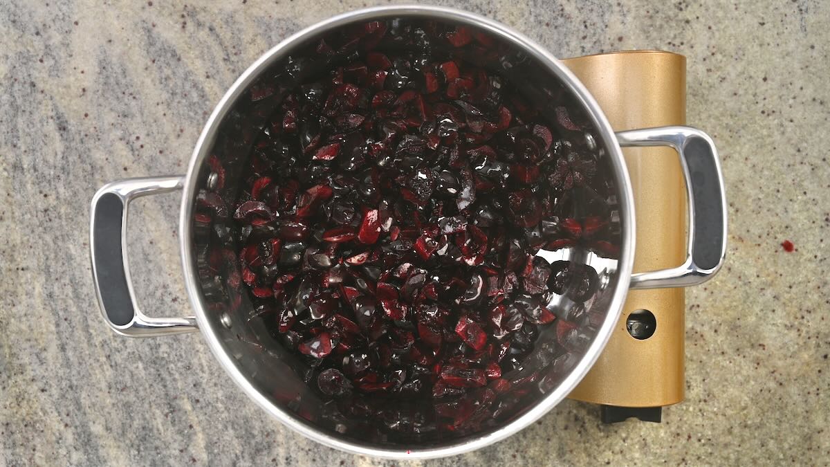 Pitted and halved cherries in a large saucepan.