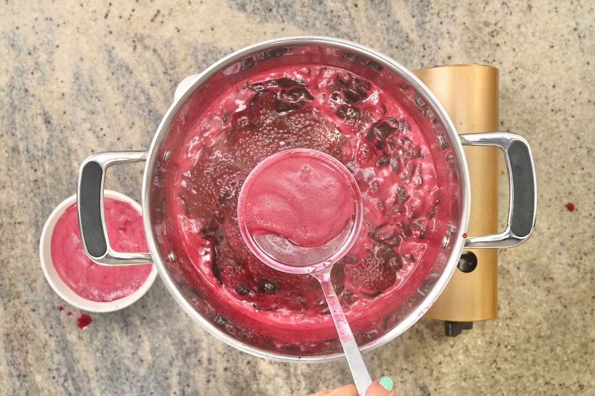 Removing foam while cooking down cherry jam.