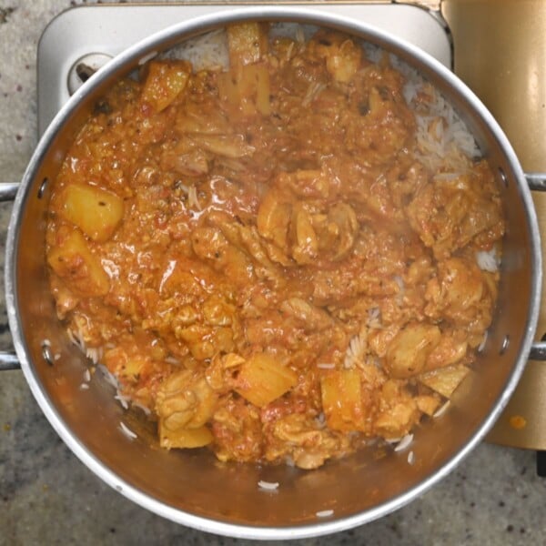 Adding cooked chicken over rice.