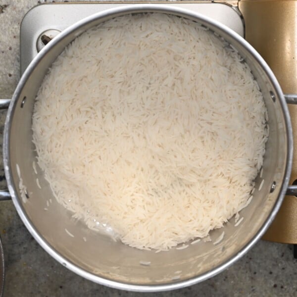 Layering cooked rice at the bottom of a large pot.