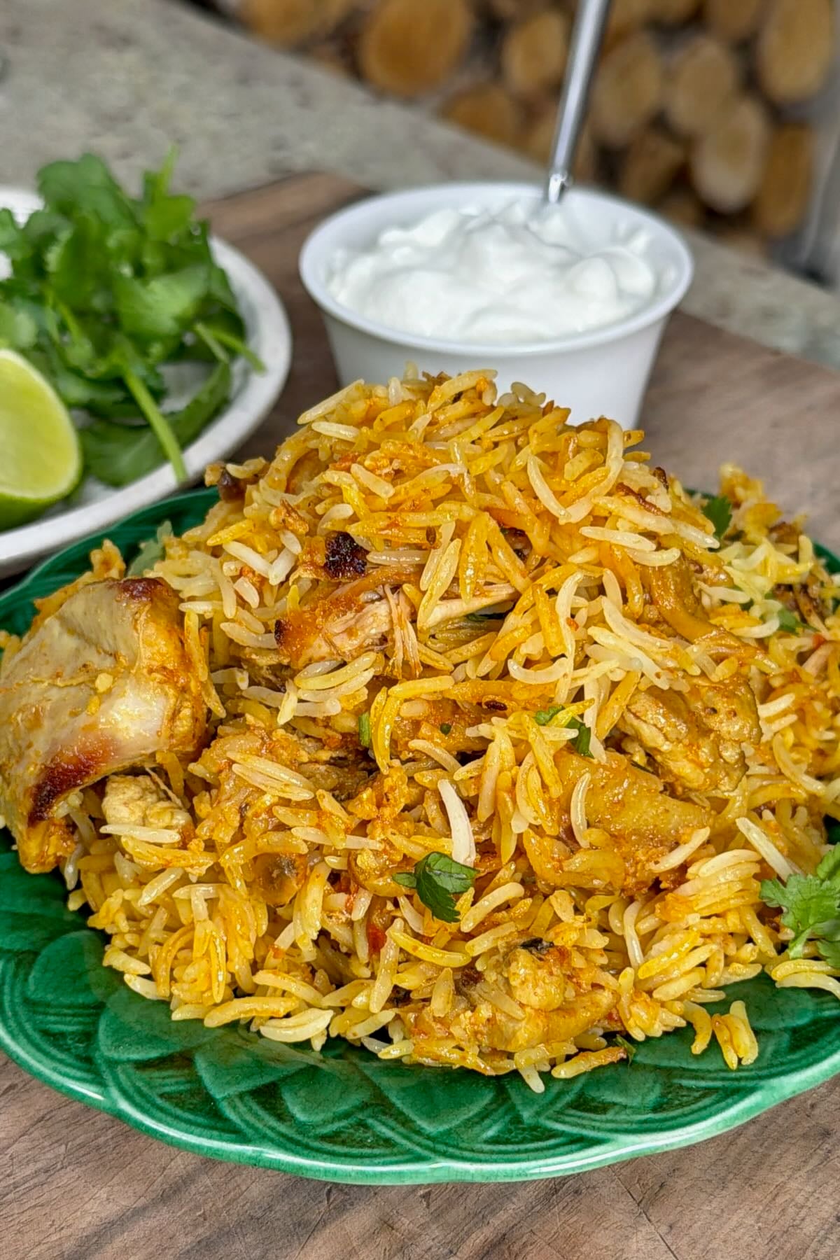 A serving of freshly made chicken biryani on a green plate.