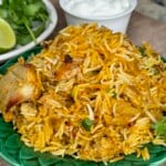 A serving of freshly made chicken biryani on a green plate.