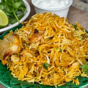 A serving of freshly made chicken biryani on a green plate.