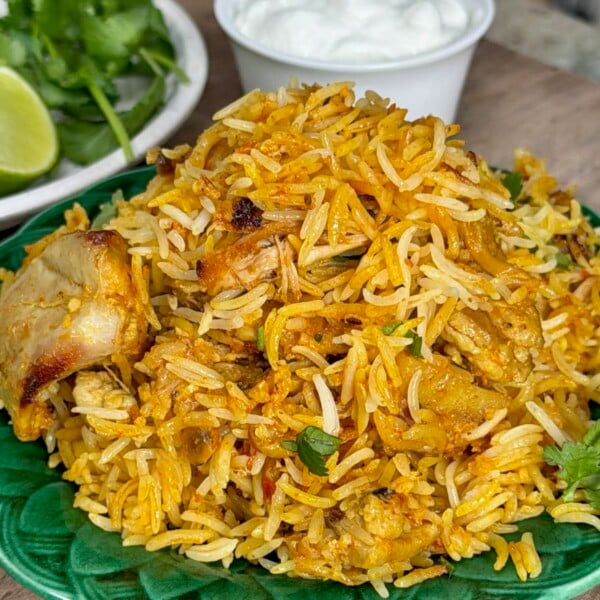 A serving of freshly made chicken biryani on a green plate.