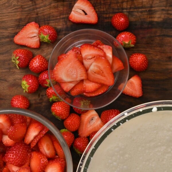 Adding strawberry slices in a glass.