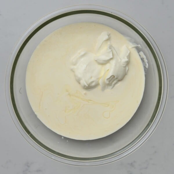 Sour cream and consdensed milk added to a bowl.