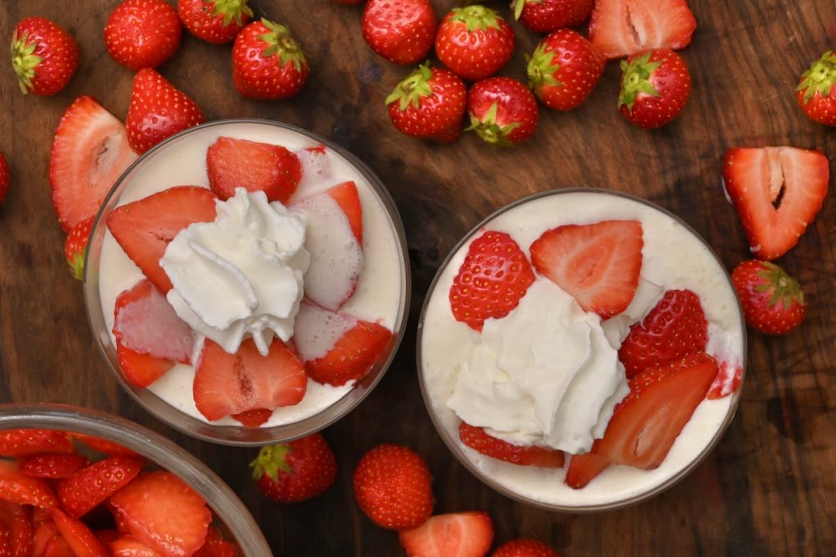 Two coupes with fresas con crema topped with strawberries and whipped cream.
