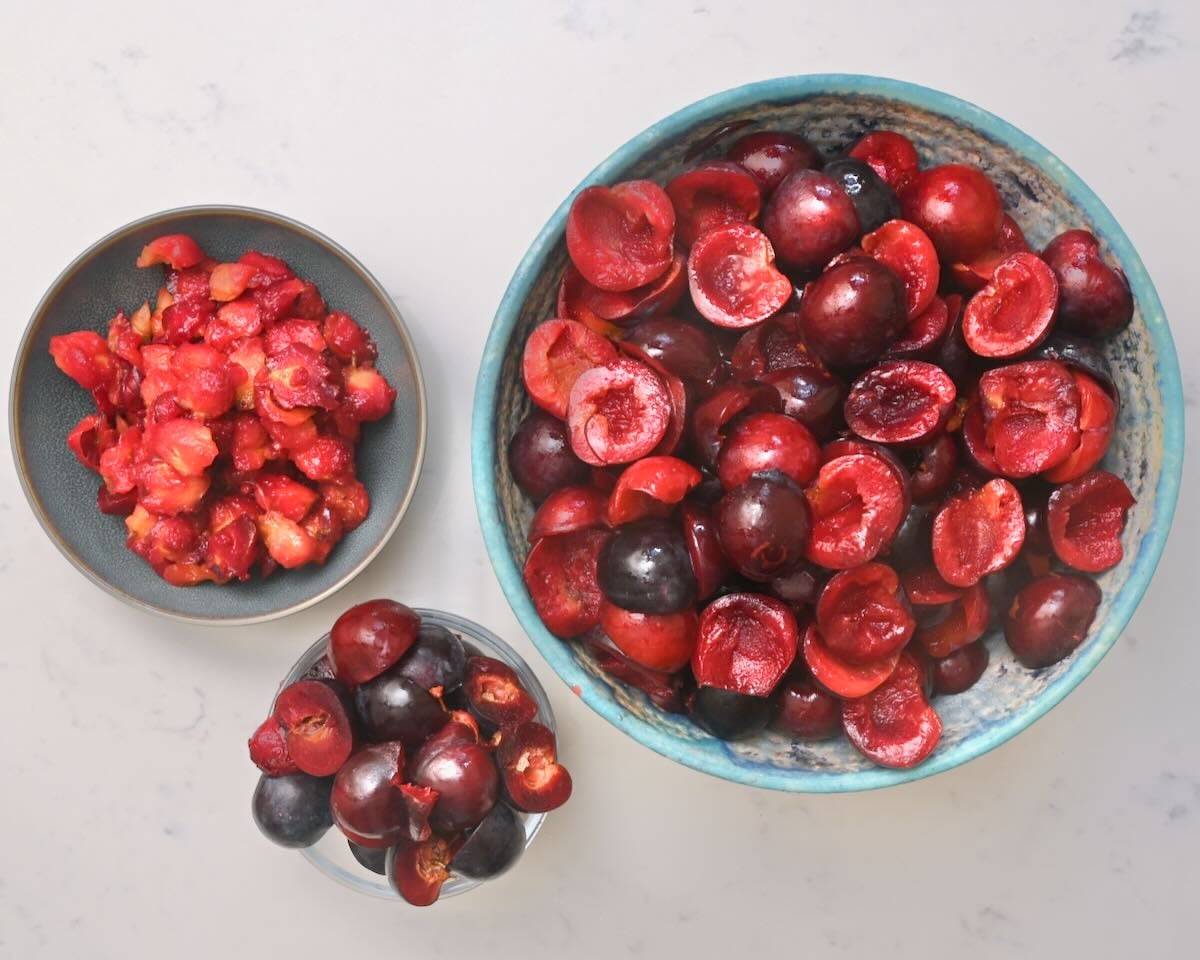 A bowl of halved plums with the stones removed.