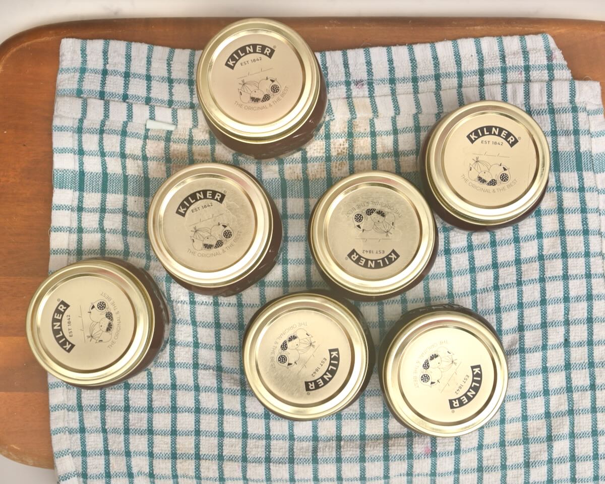 Jars with plum jam resting on a towel.