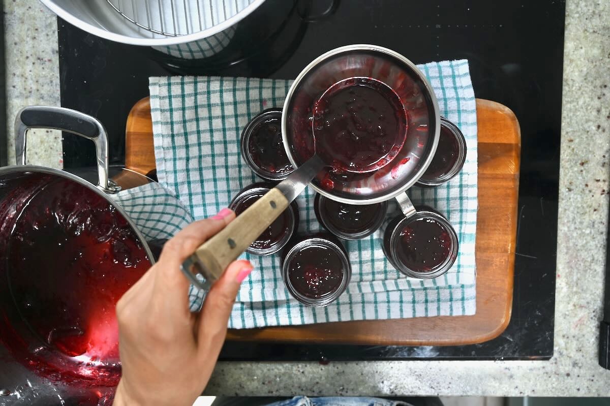 Ladling plum jam into jars.